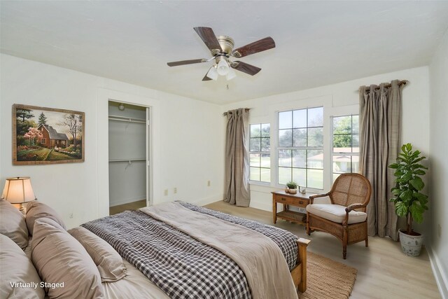 bedroom with a spacious closet, ceiling fan, light wood-type flooring, and a closet