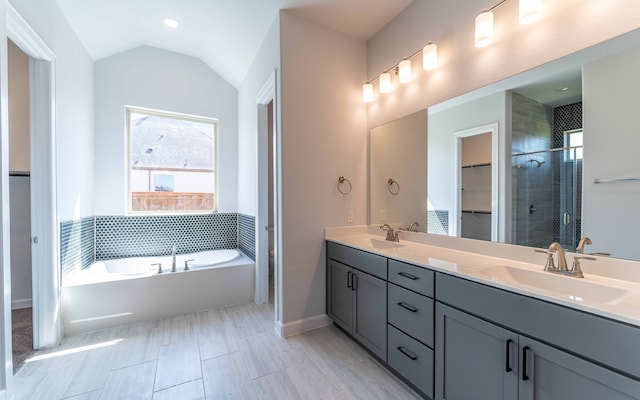 bathroom with shower with separate bathtub, vaulted ceiling, and vanity