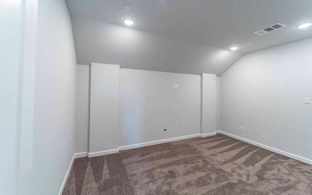 empty room with lofted ceiling and dark colored carpet