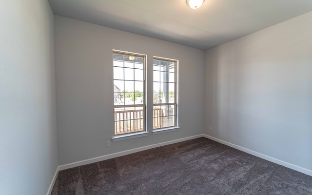 spare room featuring dark carpet