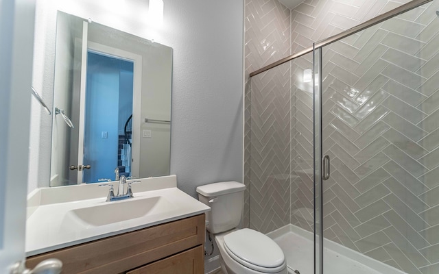 bathroom with a shower with door, vanity, and toilet