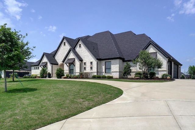 french provincial home with a front yard and a garage