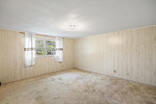 carpeted empty room with a textured ceiling and wooden walls