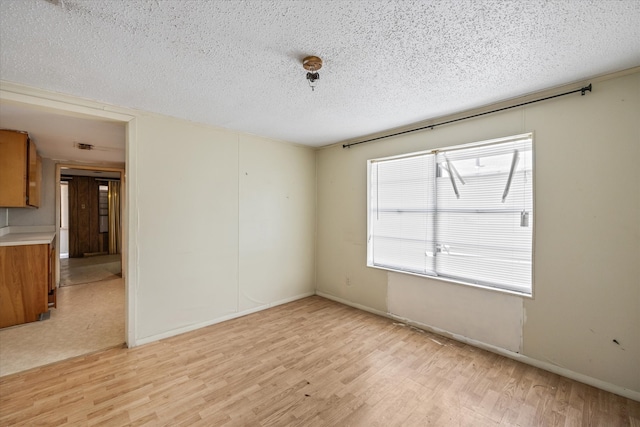 unfurnished room featuring a textured ceiling and light wood-type flooring