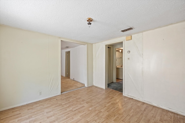 spare room with light hardwood / wood-style floors and a textured ceiling