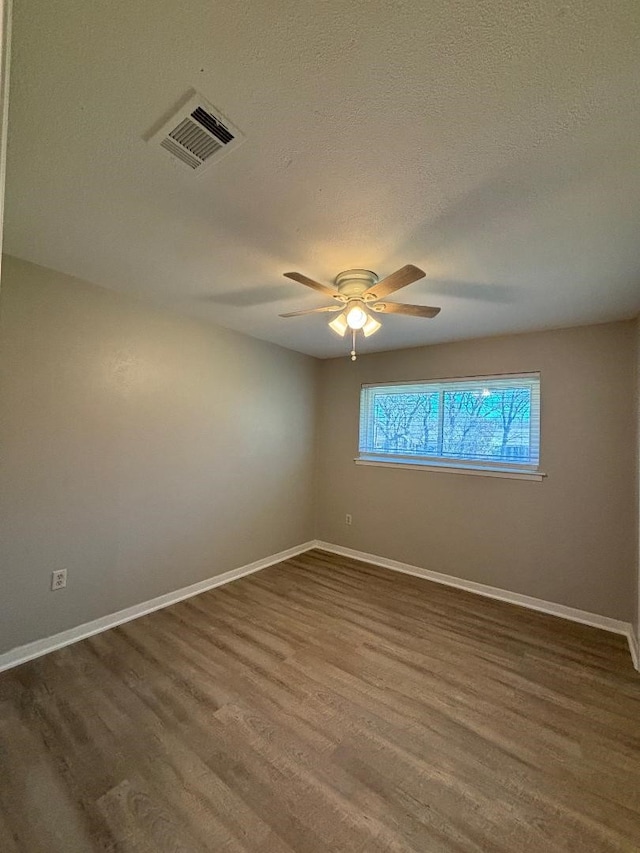 empty room with dark wood-type flooring, ceiling fan, and a textured ceiling