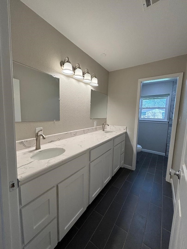 bathroom with toilet and double sink vanity