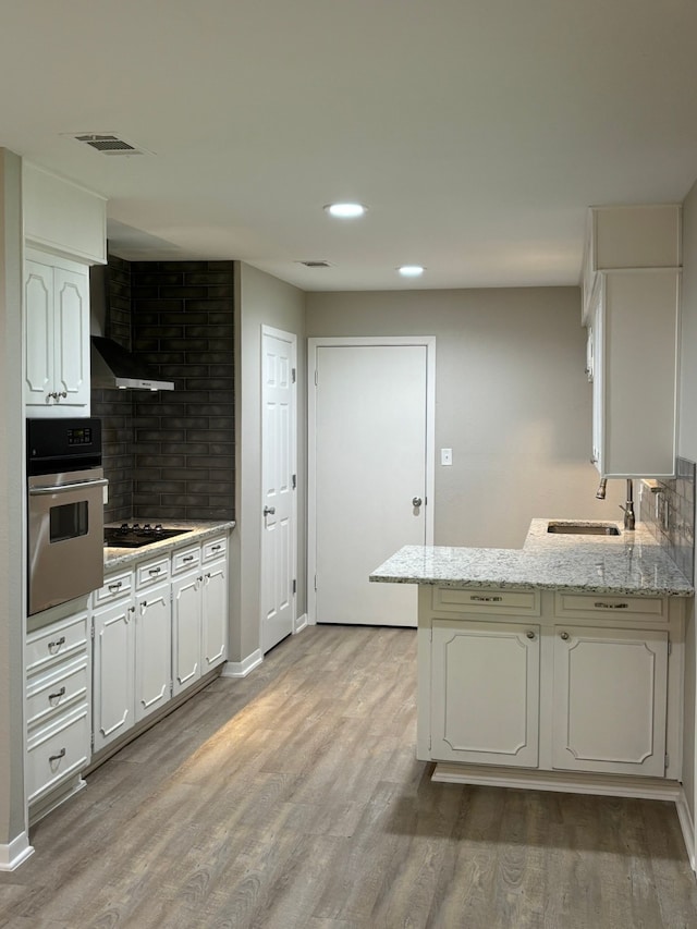 kitchen with stainless steel oven, black electric cooktop, sink, and light hardwood / wood-style floors