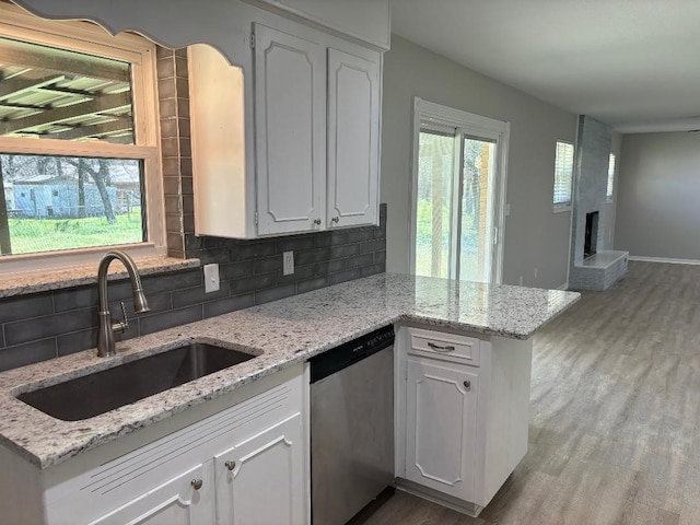 kitchen with stainless steel dishwasher, white cabinets, hardwood / wood-style flooring, sink, and tasteful backsplash