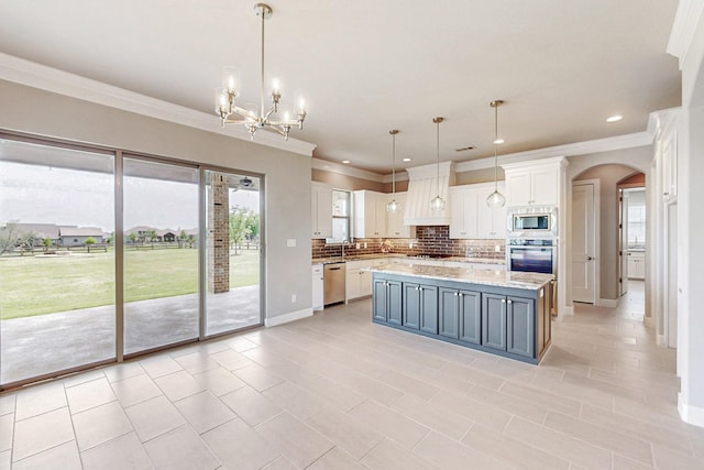 kitchen featuring pendant lighting, backsplash, white cabinets, a kitchen island, and stainless steel appliances