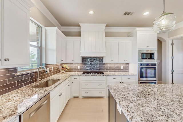 kitchen featuring appliances with stainless steel finishes, custom exhaust hood, sink, white cabinets, and hanging light fixtures