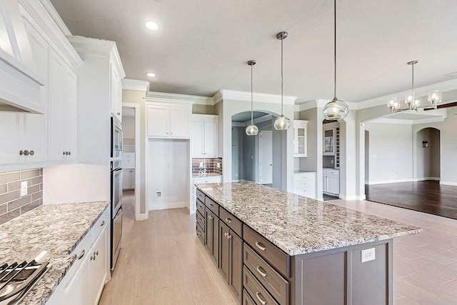 kitchen featuring decorative light fixtures, a kitchen island, white cabinetry, and tasteful backsplash