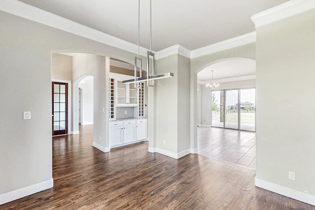 unfurnished dining area featuring ornamental molding, dark wood-type flooring, and a chandelier