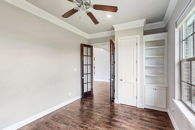 unfurnished room with ceiling fan, dark wood-type flooring, a healthy amount of sunlight, and ornamental molding