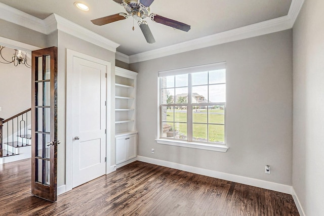 unfurnished room featuring ceiling fan with notable chandelier, ornamental molding, and dark wood-type flooring