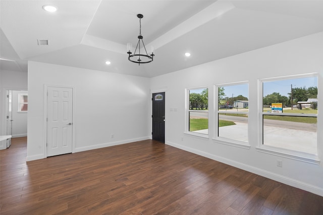 unfurnished room with a tray ceiling, dark hardwood / wood-style floors, and a notable chandelier