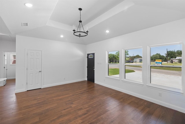 spare room with dark wood-style floors, baseboards, an inviting chandelier, recessed lighting, and a raised ceiling