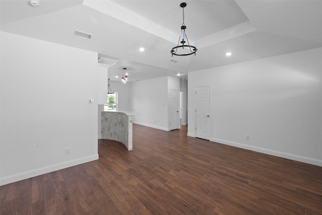 spare room featuring a tray ceiling, baseboards, visible vents, and dark wood-style flooring