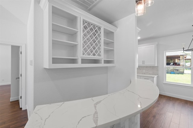 corridor with baseboards, visible vents, and dark wood-style flooring