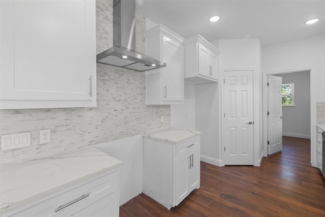 kitchen with dark hardwood / wood-style flooring, tasteful backsplash, light stone counters, wall chimney exhaust hood, and white cabinetry