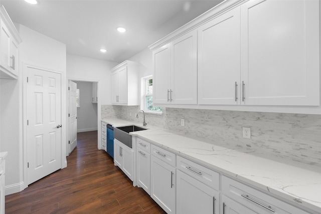 kitchen with light stone countertops, a sink, decorative backsplash, dark wood-type flooring, and white cabinets