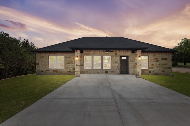 view of front of property with stone siding, a shingled roof, and a yard