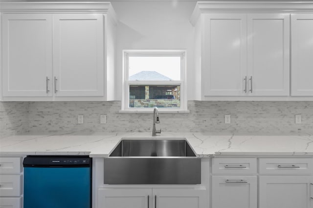 kitchen with backsplash, light stone countertops, dishwashing machine, white cabinetry, and a sink