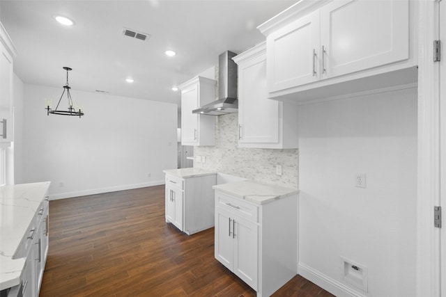 kitchen featuring light stone counters, visible vents, dark wood finished floors, wall chimney range hood, and backsplash