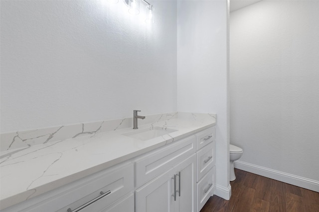 bathroom with baseboards, toilet, wood finished floors, and vanity