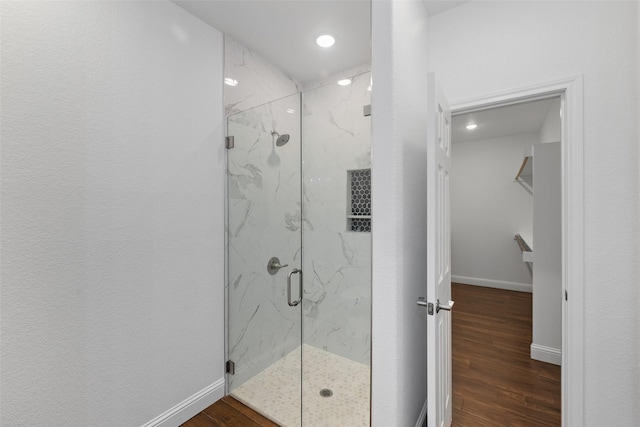 full bath featuring a marble finish shower, baseboards, and wood finished floors