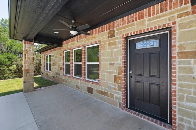 entrance to property with brick siding and a ceiling fan