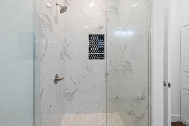 full bath with a marble finish shower and a textured wall