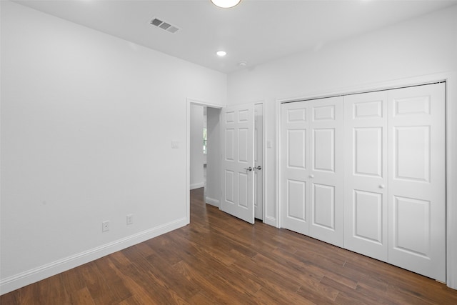 unfurnished bedroom featuring a closet and dark wood-type flooring