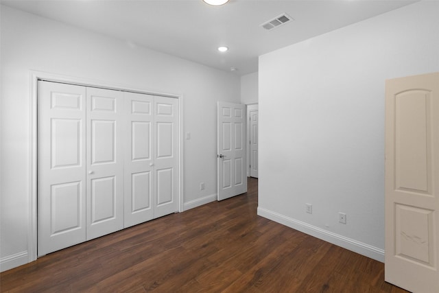 unfurnished bedroom featuring a closet, visible vents, dark wood-type flooring, and baseboards