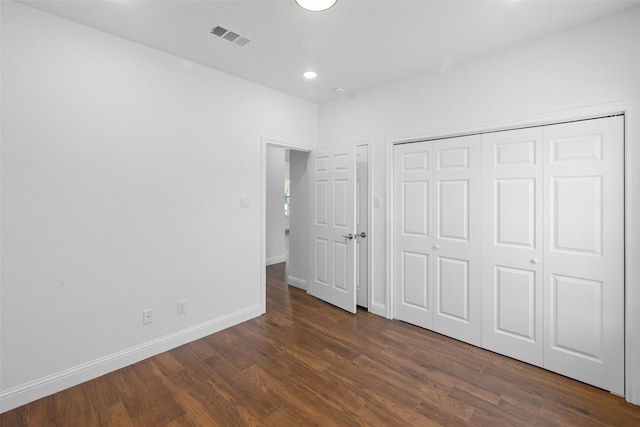 unfurnished bedroom with a closet, baseboards, visible vents, and dark wood-style flooring