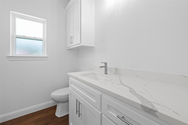 bathroom featuring baseboards, toilet, wood finished floors, and vanity