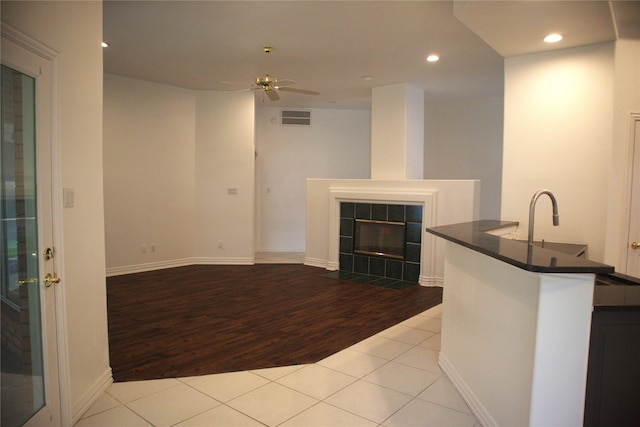 interior space featuring ceiling fan, a tile fireplace, sink, and light tile floors