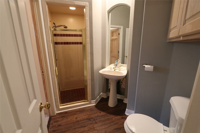 bathroom with a shower with shower door, toilet, and wood-type flooring