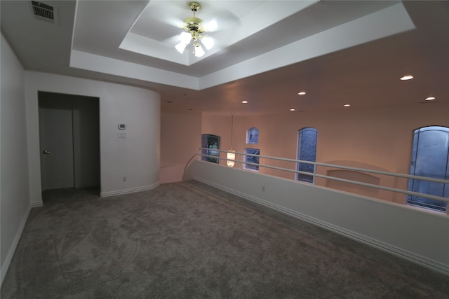 carpeted spare room featuring a tray ceiling and ceiling fan