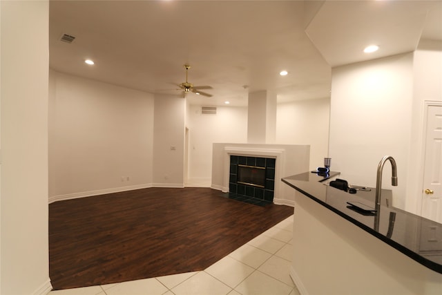 unfurnished living room featuring ceiling fan, light hardwood / wood-style floors, and a fireplace