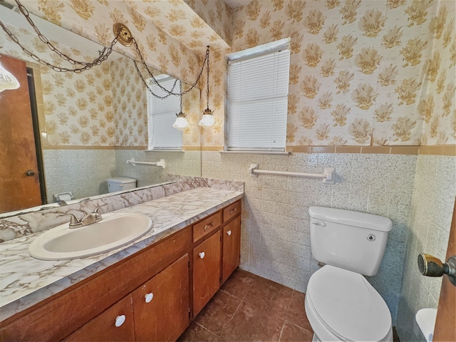 bathroom with tile patterned floors, vanity, toilet, and tile walls