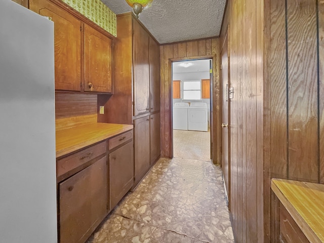 interior space featuring separate washer and dryer, wood walls, and a textured ceiling