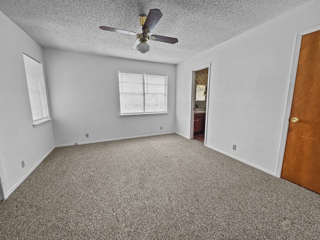 unfurnished bedroom featuring ensuite bath, ceiling fan, carpet floors, and multiple windows