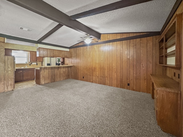 kitchen featuring vaulted ceiling with beams, ceiling fan, light carpet, and a textured ceiling