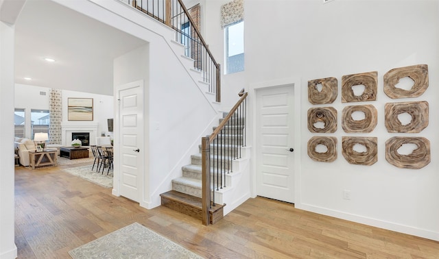 staircase with a towering ceiling and light hardwood / wood-style floors