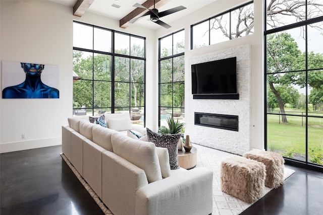 living room featuring beamed ceiling, ceiling fan, plenty of natural light, and concrete flooring