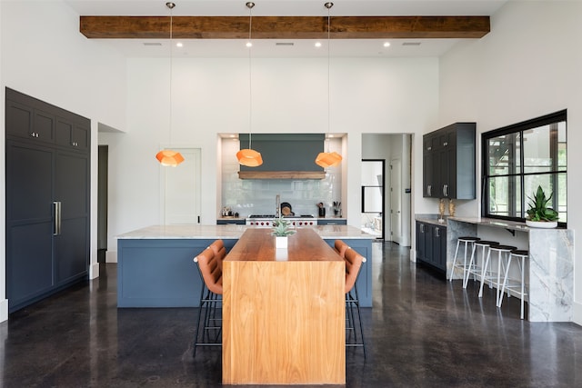 kitchen with a kitchen bar, a towering ceiling, decorative light fixtures, beamed ceiling, and a center island