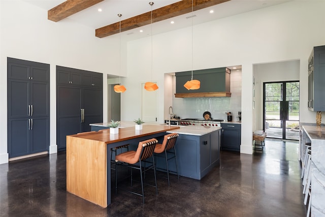 kitchen with a kitchen bar, a towering ceiling, pendant lighting, beamed ceiling, and an island with sink