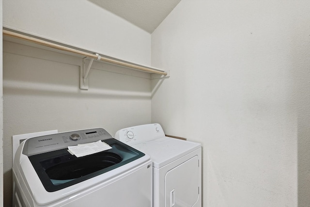 clothes washing area with a textured ceiling and independent washer and dryer