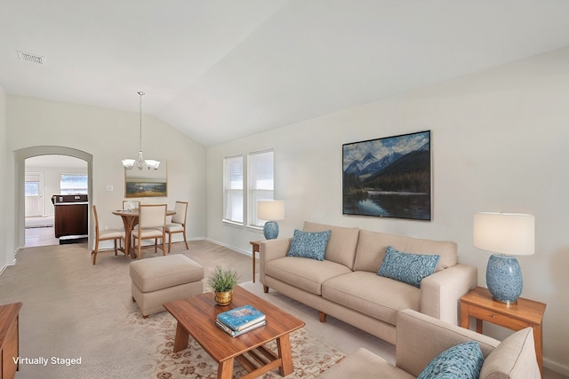 living room featuring light colored carpet, vaulted ceiling, and an inviting chandelier